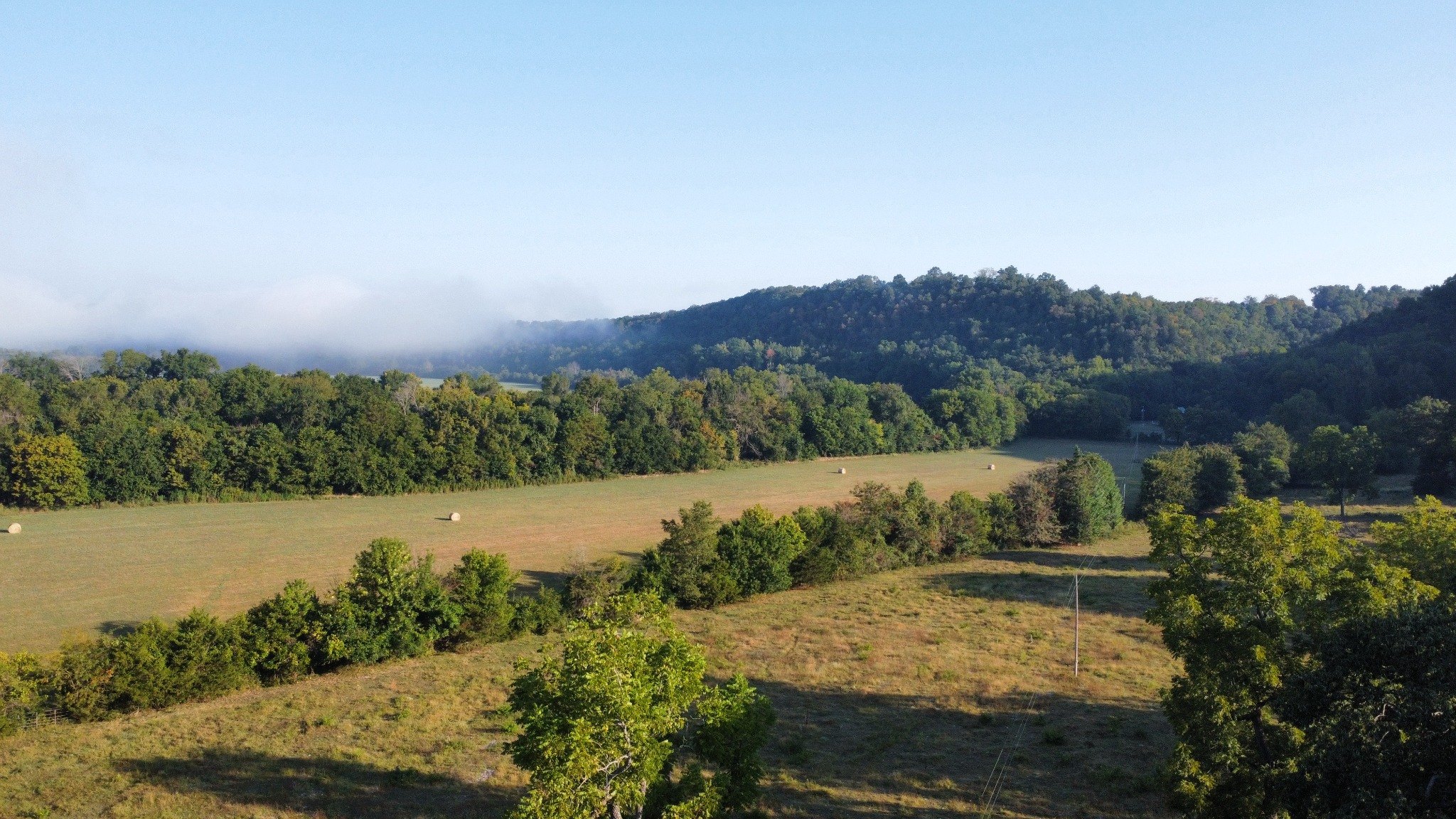 Morning view across fields toward wooded Ozark hills